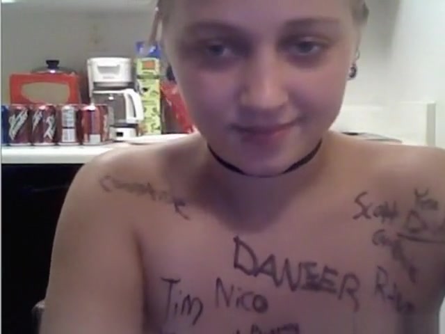 Ponytailed blonde girl writes all kinds of words on her naked body in the kitchen